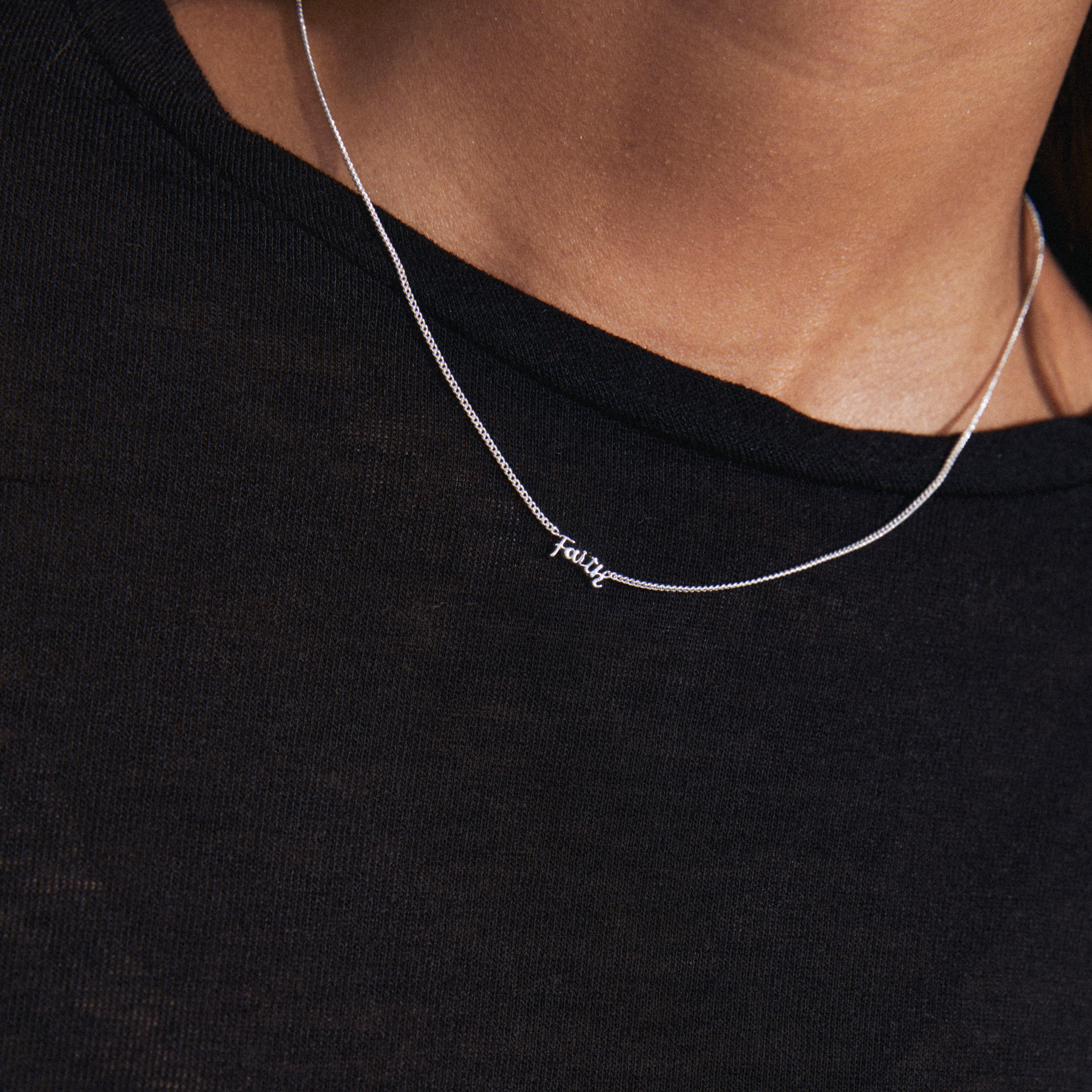 FAITH necklace silver-plated, shown worn, featuring a sleek design and small cursive 'FAITH' pendant, perfect for layering or solo wear.