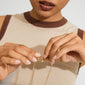 A young woman fastens a gold-plated Lock with 2 lobsters clasp, showcasing its versatility for layering necklaces without tangling.