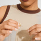 Hands holding a delicate gold-plated Lock with 2 Lobsters clasp, designed to layer necklaces without tangling, reflecting Pilgrim's Scandinavian craftsmanship and modern style.