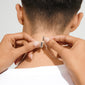 Hands fastening a silver-plated Lock with 2 lobsters clasp, perfect for layering necklaces without tangling, shown on a short-haired person in a white T-shirt.