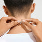 Hands fasten a silver-plated Lock with 2 lobsters clasp necklace on a person's neck, showcasing two elegantly draped chains designed for a layered look.