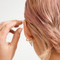 Close-up of pastel-pink hair with gold-plated bullet locks on stud earrings, showcasing Pilgrim's blend of timeless and trendy Scandinavian jewelry.