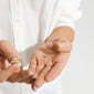 Hands hold a Bullet, 7 mm gold-plated stud earring. One hand grips the front post; the other displays the earring back. Two-piece set from Pilgrim.