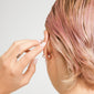 Hand tucks pink-blonde hair behind pierced ear, showcasing silver-plated 5 mm bullet lock beads on stud earrings. Two-piece set from Pilgrim's Scandinavian-inspired collection.