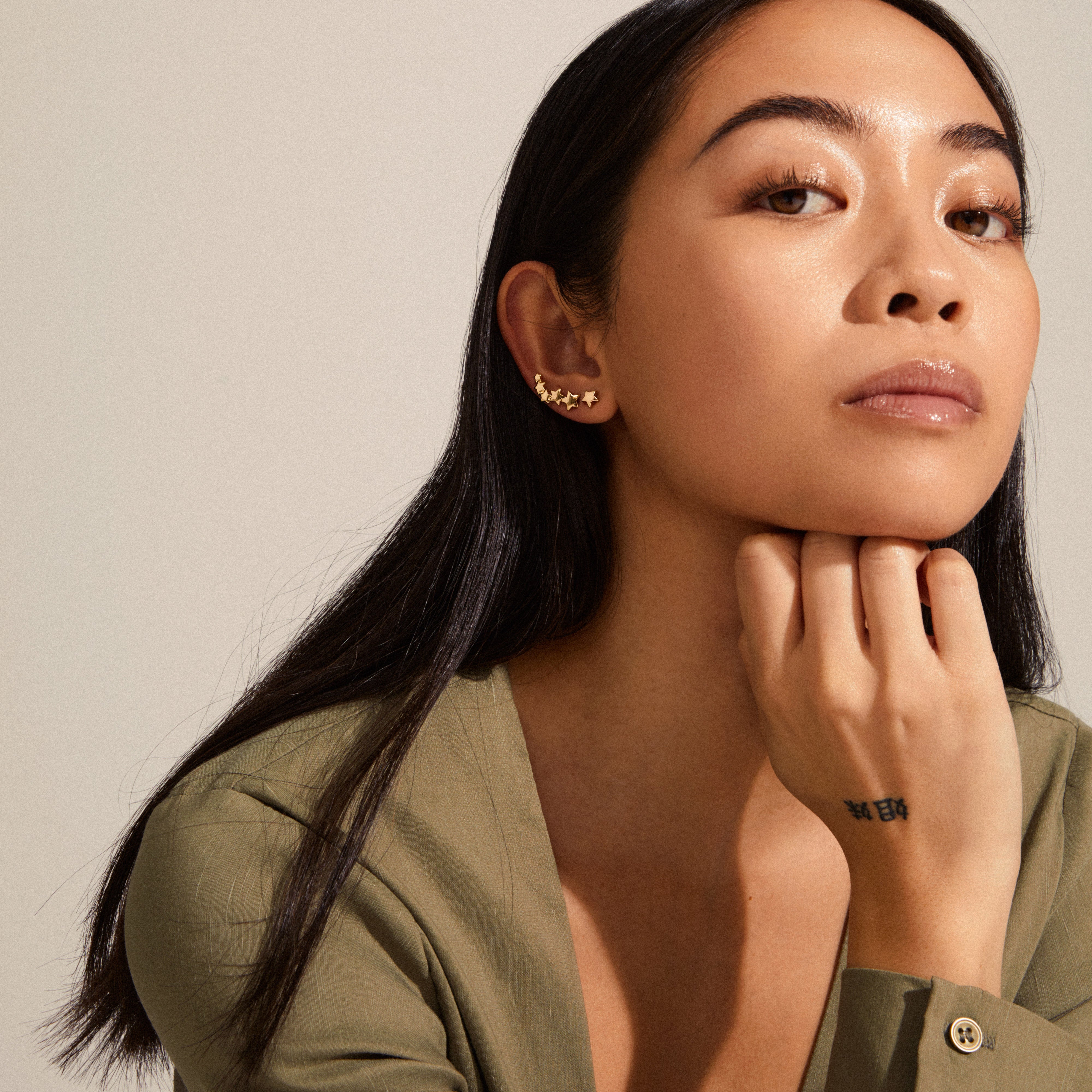 Woman wearing AVA star earrings gold-plated, featuring an asymmetrical design with a shooting star along the ear and a small stud.