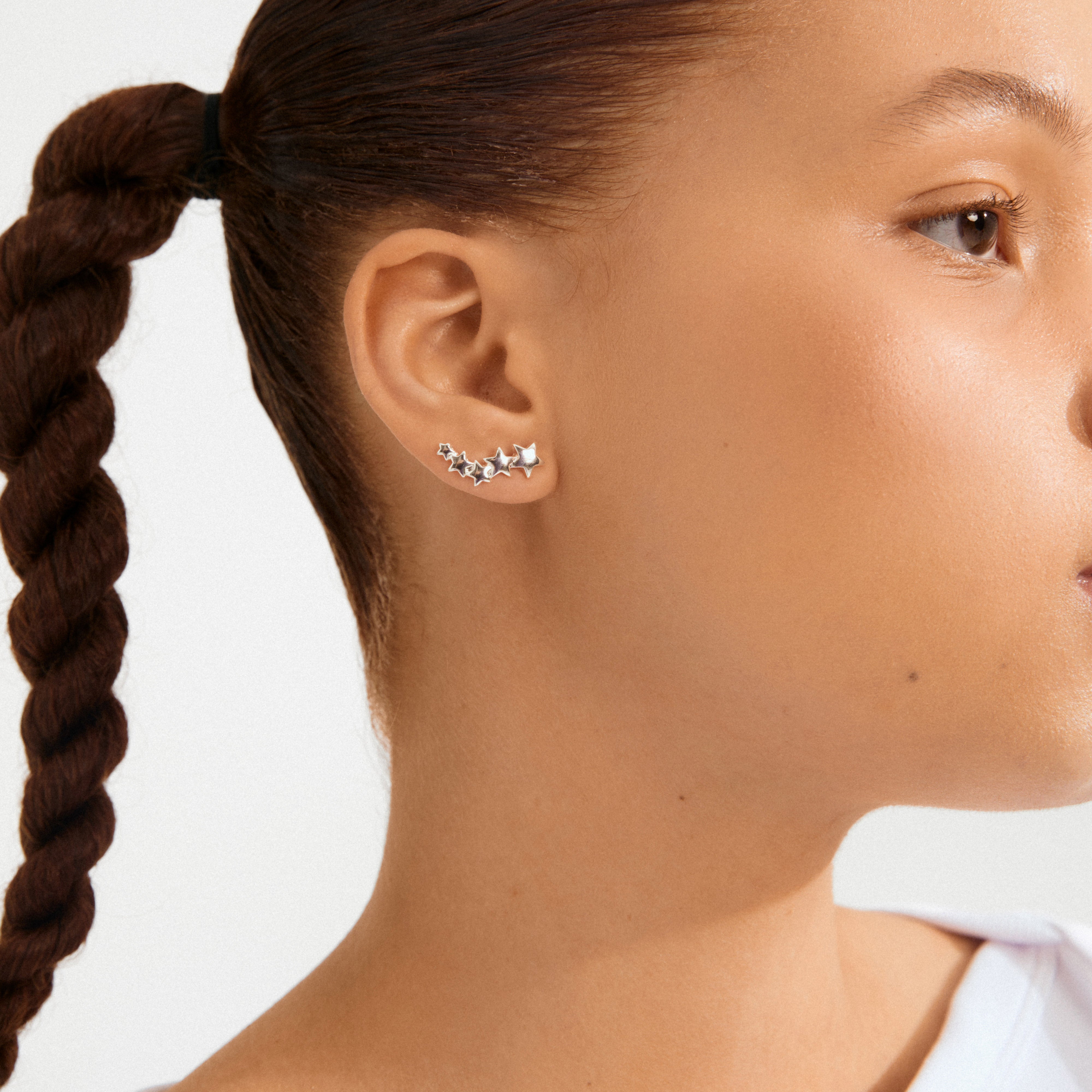 Profile view showcasing AVA star earrings silver-plated, featuring a series of small, silver stars climbing the earlobe in an elegant, asymmetrical design.