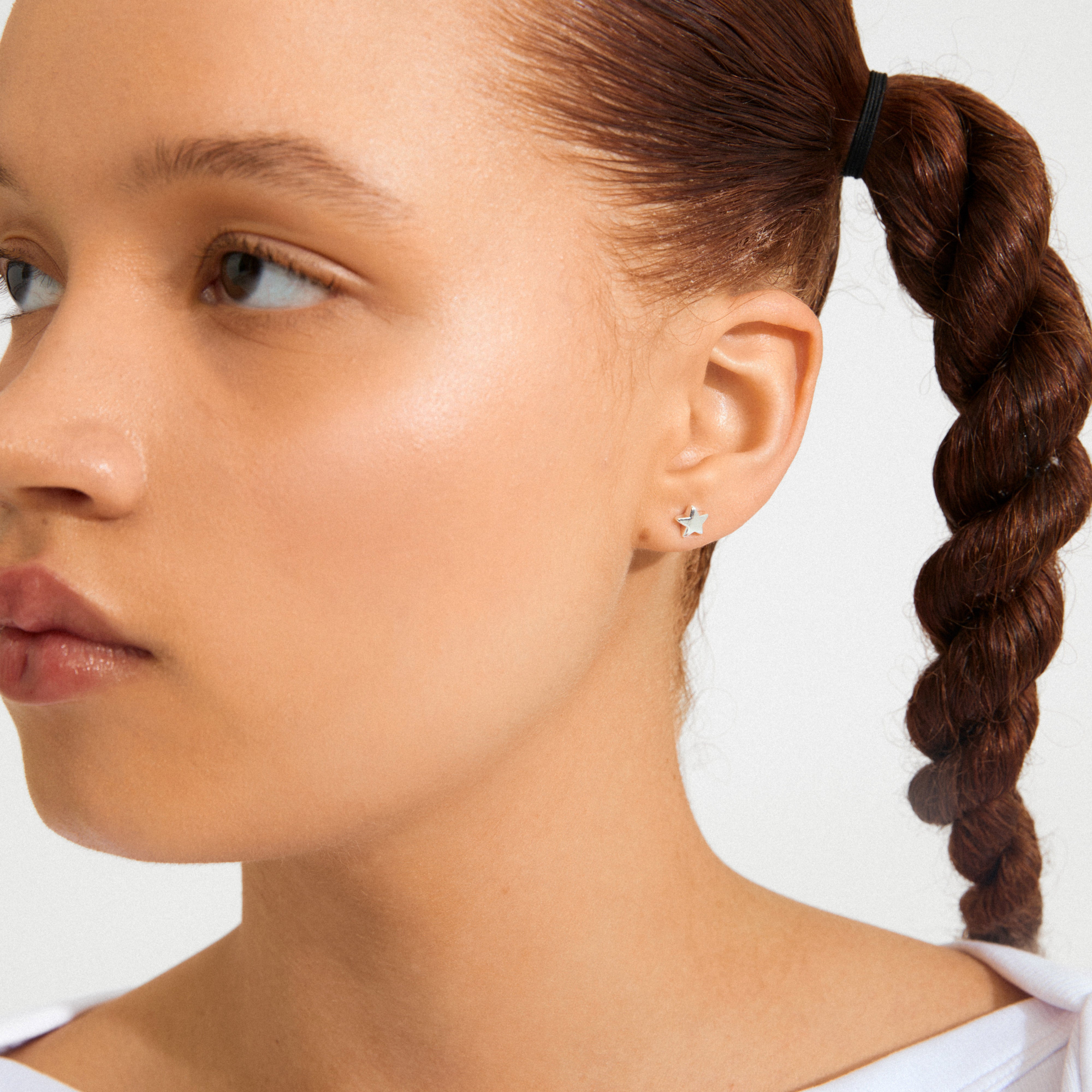 Side view of a person wearing AVA star earrings, featuring a silver-plated star stud. The focus is on the smooth skin and elegant jewelry.