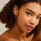 LAYLA medium hoop earrings gold-plated, showcased on a woman with curly hair, emphasizing the elegant, timeless design and user-friendly click clasp.