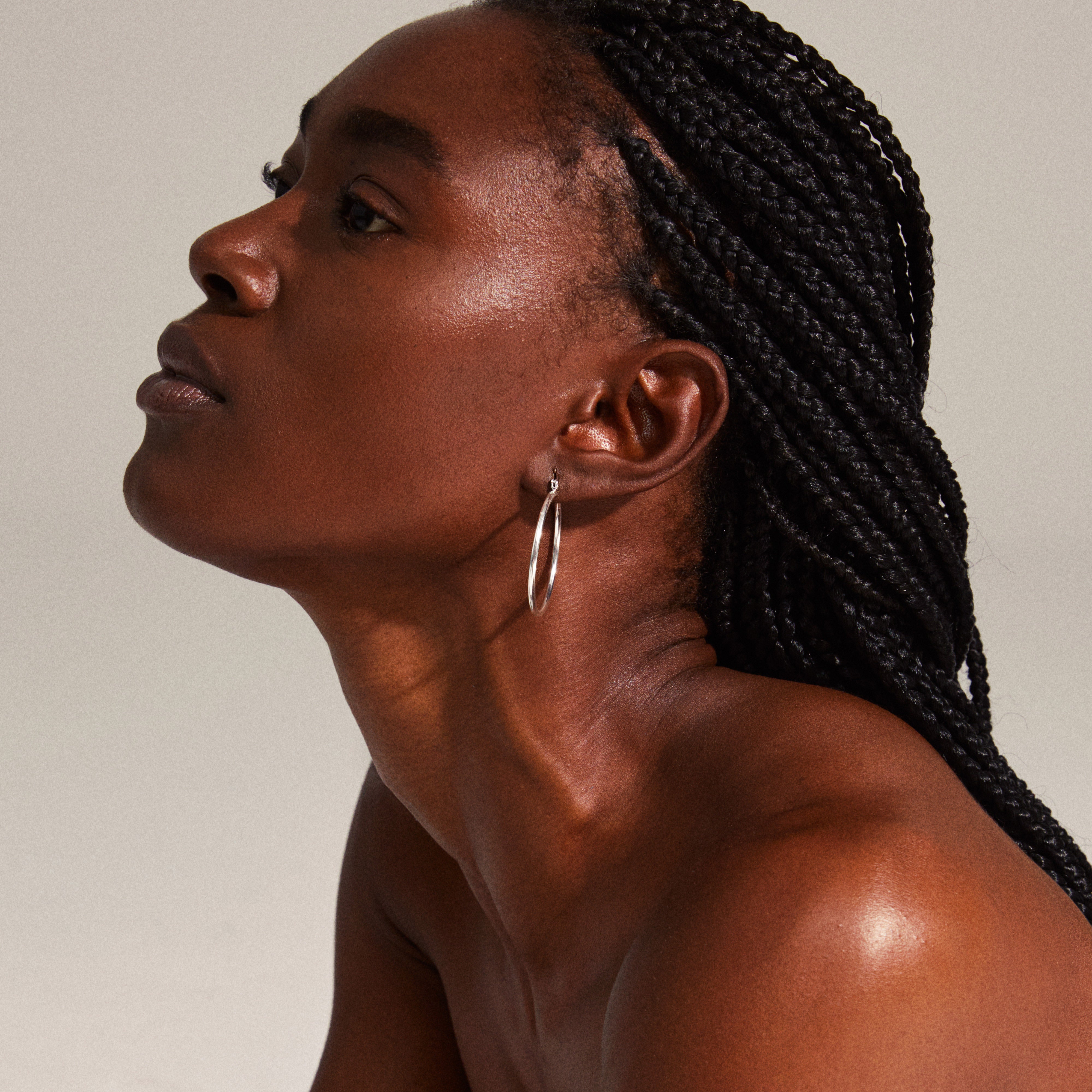 LAYLA large hoop earrings silver-plated worn by a woman with braided hair looking up, showcasing elegant, medium-sized creoles enhancing her personal style.