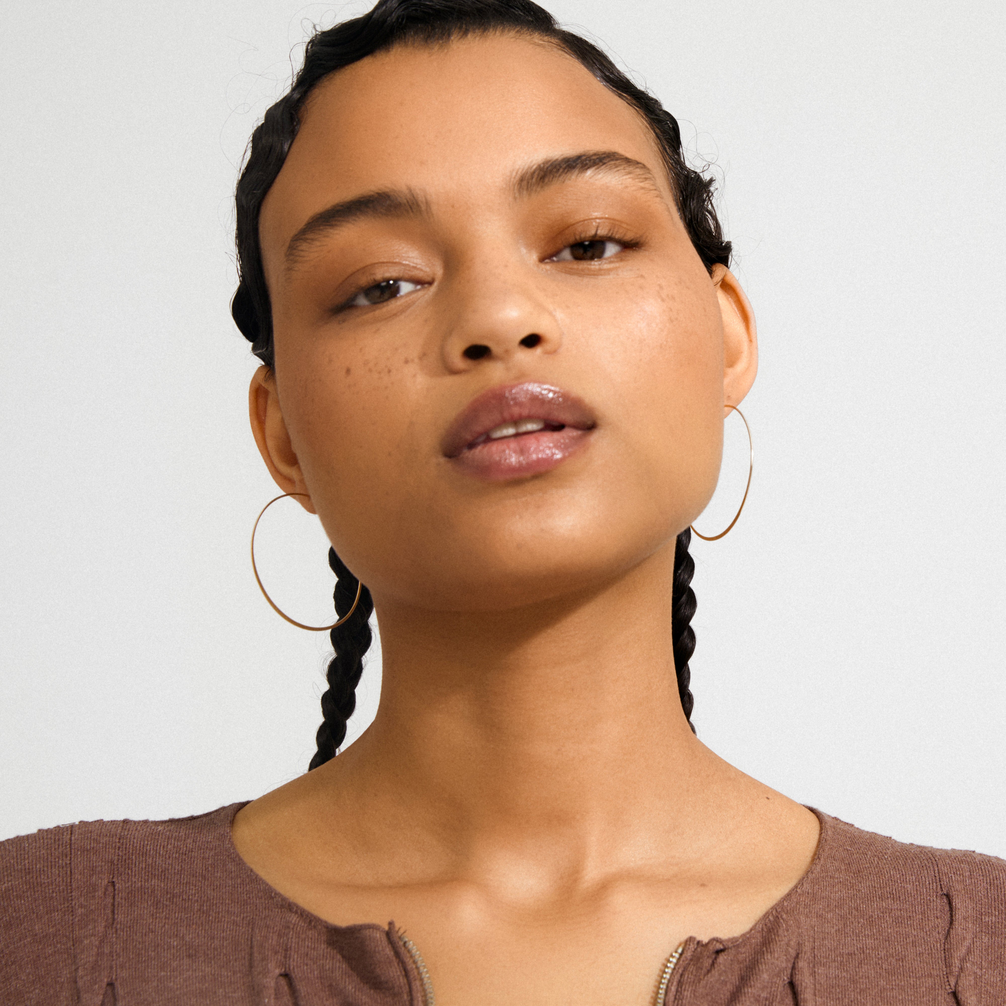 Young woman wearing Pilgrim's TILLY large gold-plated hoop earrings, showcasing their sleek, airy design as a stylish, eye-catching accessory.