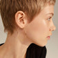 TILLY large gold-plated hoop earrings on a woman with short hair, highlighting their sleek, airy design and eye-catching size.