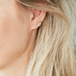 IMOGEN crystal leaf earrings gold-plated on a woman's ear, showcasing delicate leaf design with sparkling Preciosa crystals, embodying Pilgrim's blend of elegance and nature-inspired style.