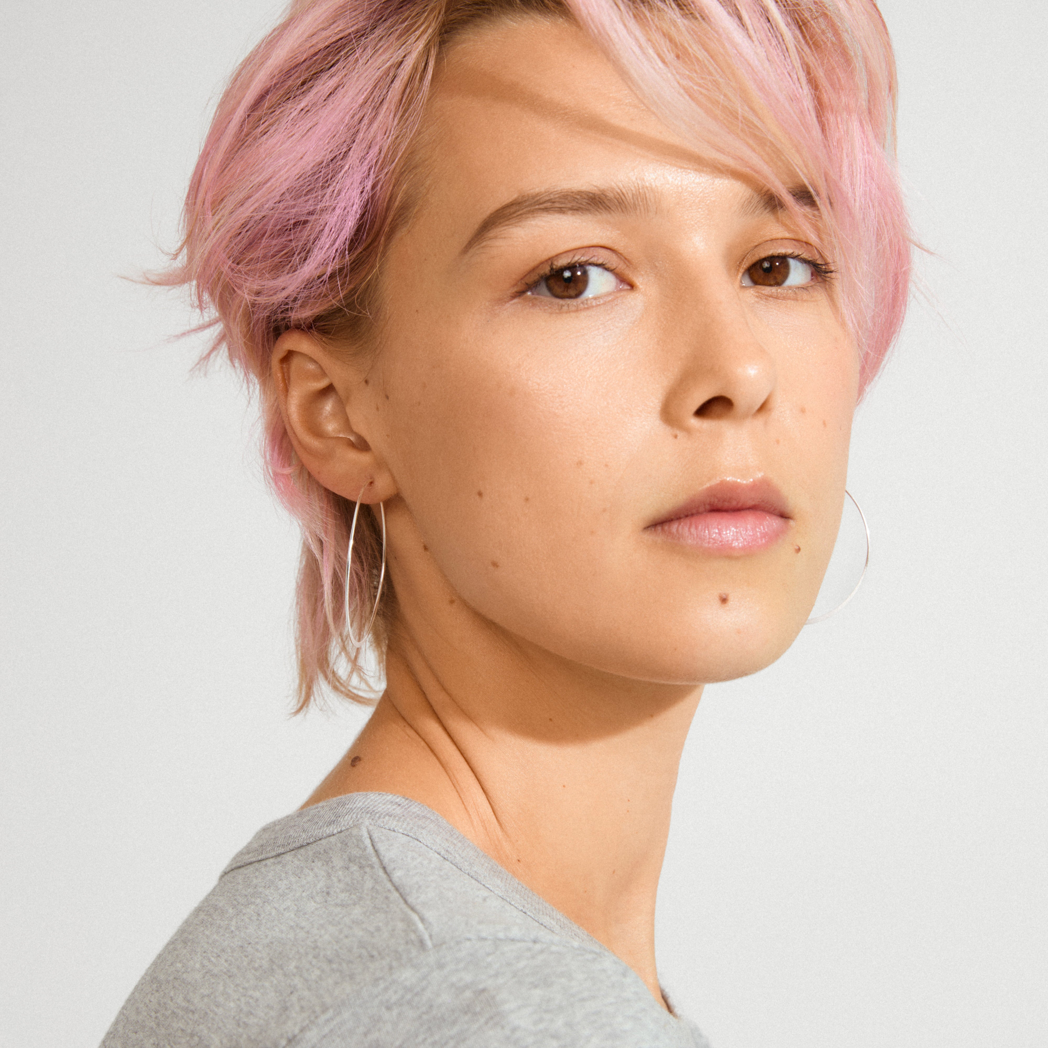 TILLY large hoop earrings silver-plated adorn a young adult with pastel-pink hair, showcasing Pilgrim's trendy, inclusive style in a close-up portrait.