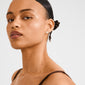 Young woman wearing Pilgrim's IMOGEN crystal leaf earrings, silver-plated, capturing light with delicate sparkling crystals, highlighting nature-inspired elegance and style.