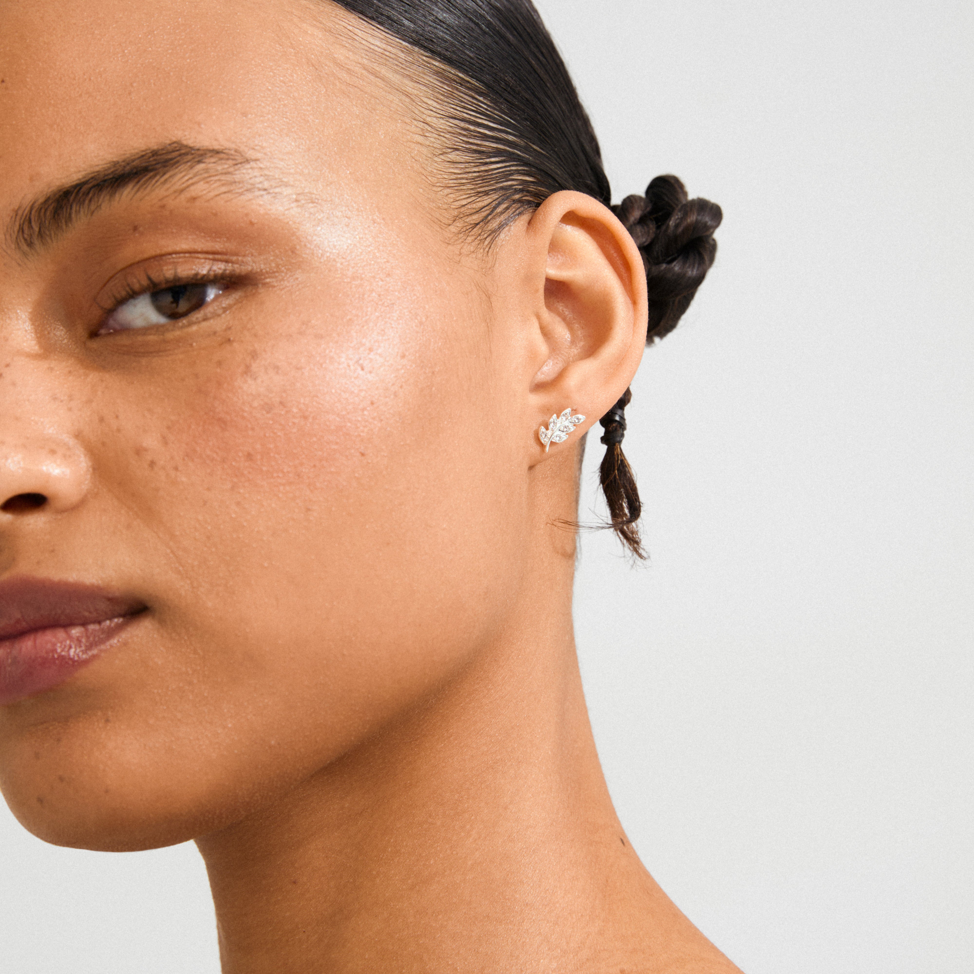 Woman wearing IMOGEN crystal leaf earrings, silver-plated with marquise-cut leaves and Preciosa crystals, highlighting Pilgrim's blend of nature-inspired elegance and Scandinavian craftsmanship.
