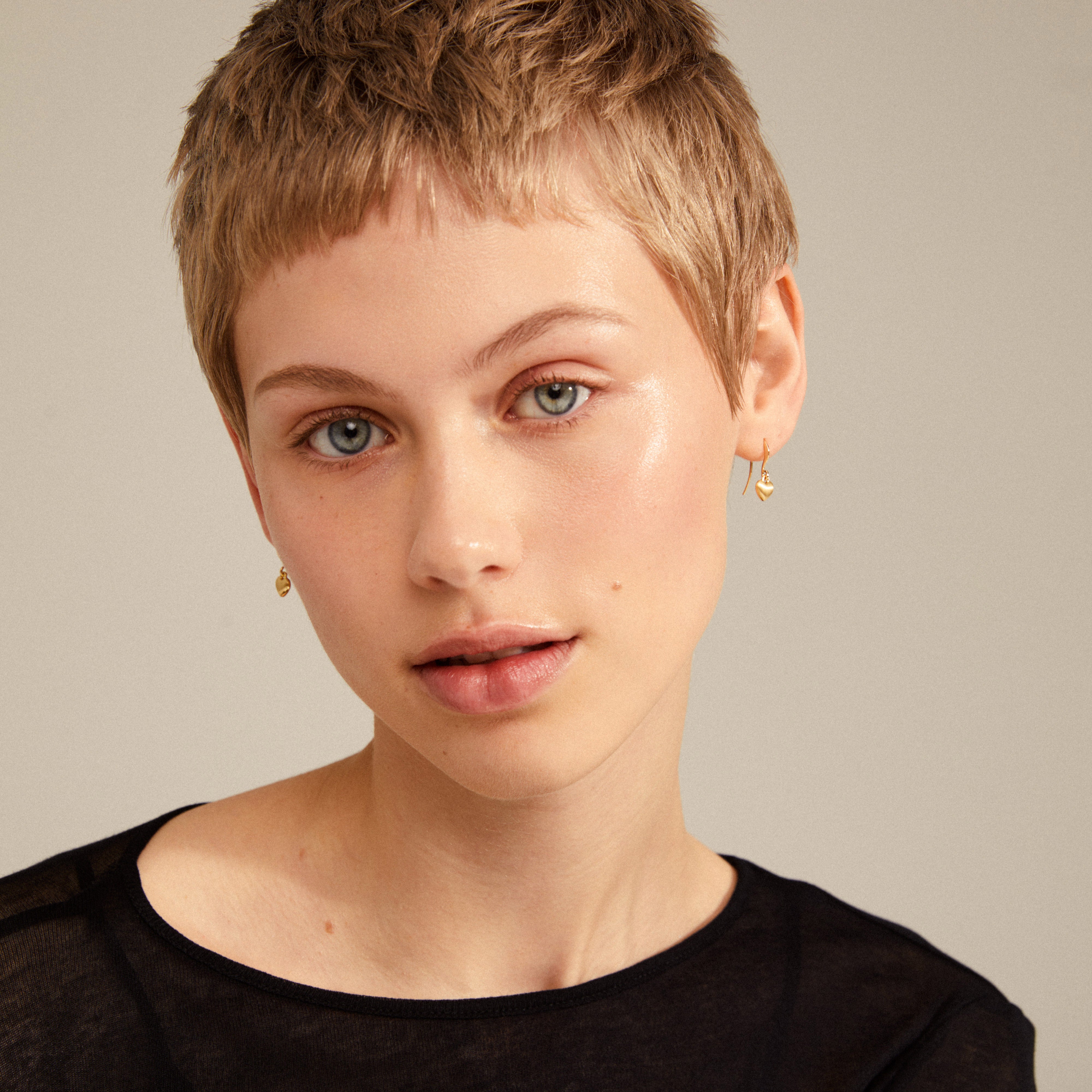 SOPHIA heart pendant earrings gold-plated, worn by a woman with short blonde hair, showcasing elegant dangle design for versatile wear.