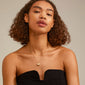 SOPHIA heart pendant necklace gold-plated, worn by a woman with curly hair, featuring a large matte heart and smaller crystal heart, elegantly resting on the collarbone.