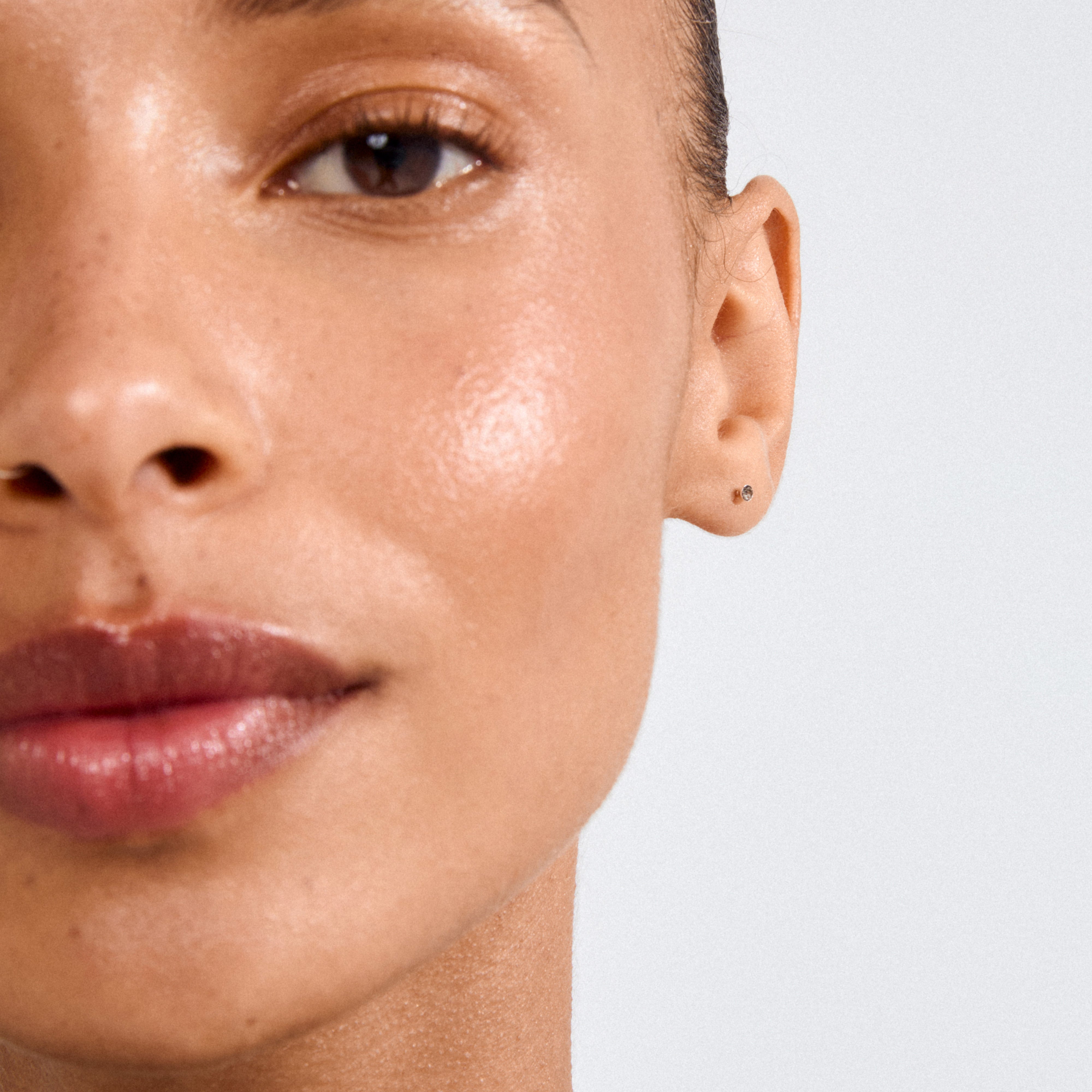 Close-up of a woman's ear wearing a YANA micro crystal earstud, showcasing the delicate silver-plated setting and sparkling Preciosa crystal.