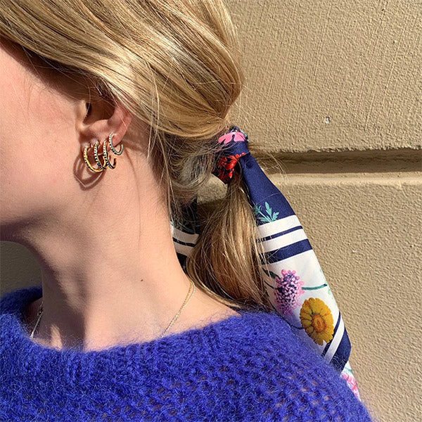 Woman wearing ROBERTA crystal semi-hoops gold-plated, showcasing medium-sized hoops with clear crystals, embodying Nordic cool simplicity and exclusivity from Pilgrim.