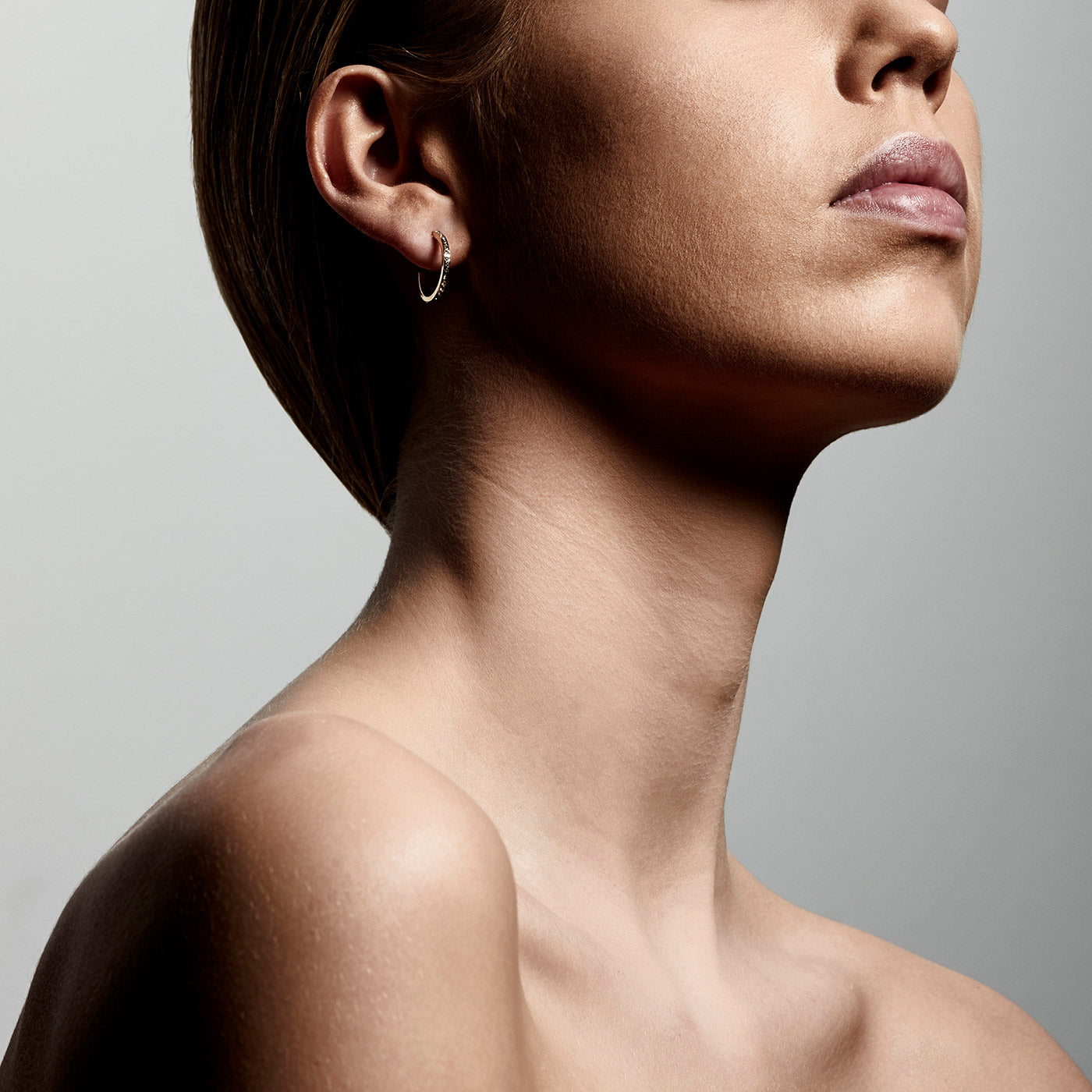 Close-up of a woman's face wearing Roberta crystal semi-hoops gold-plated, showcasing the intricate detailing and elegant Nordic-inspired design.