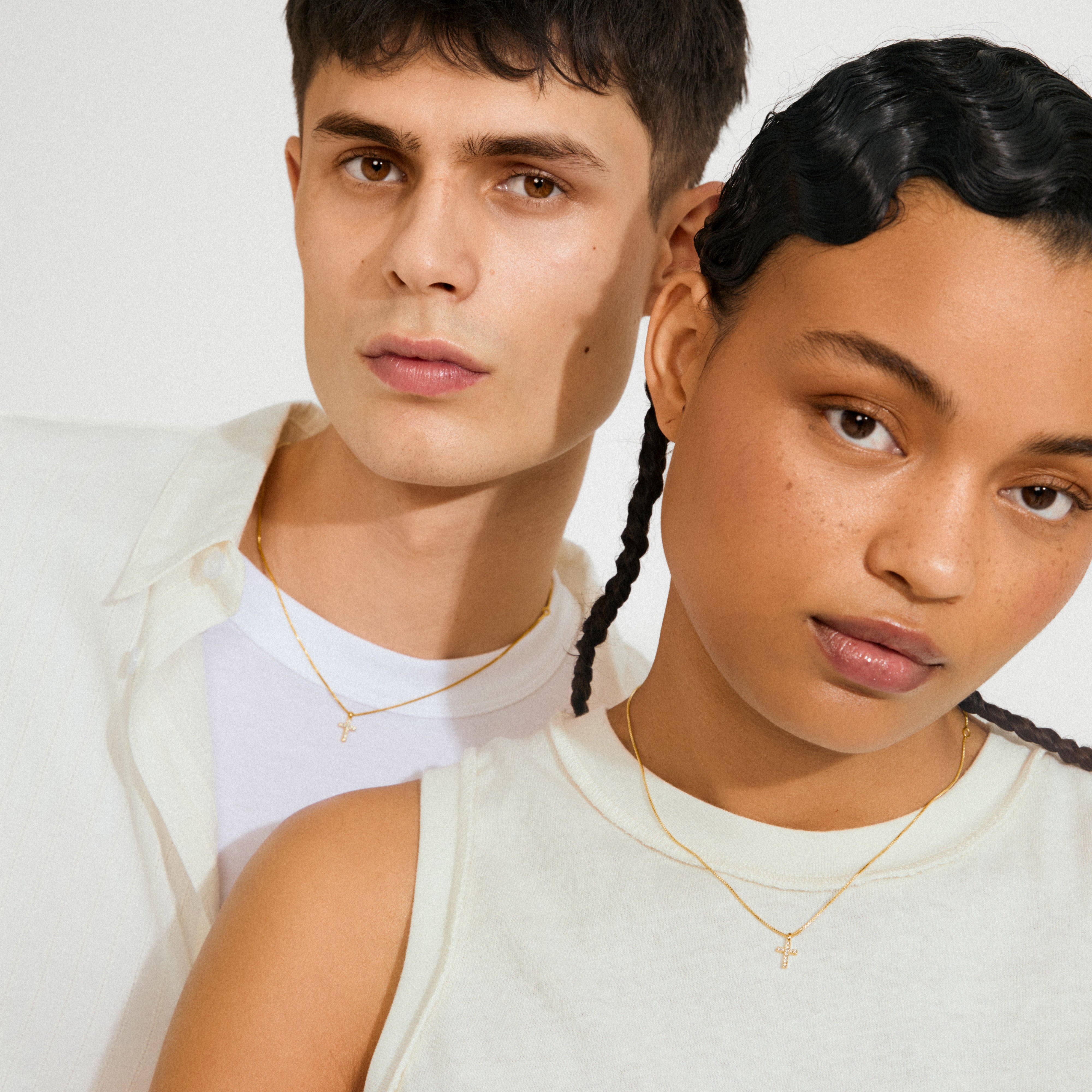 Two young adults wearing CLARA crystal cross necklace gold-plated, showcasing its sparkling crystal-adorned cross pendant and adjustable chain for a modern, minimalist look.