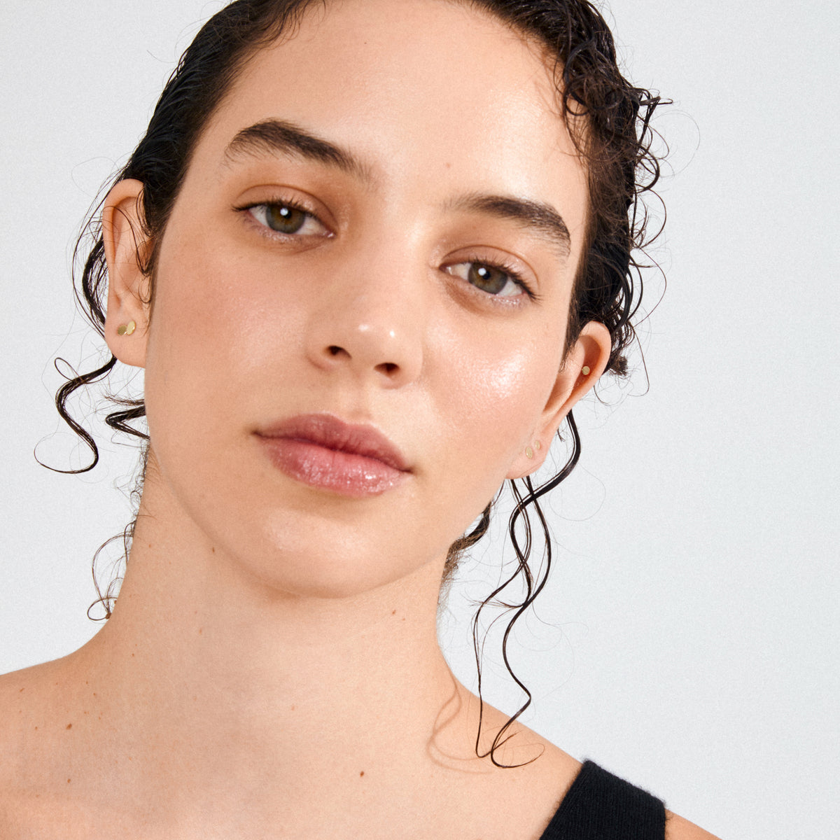 Young woman wearing NORMA 3-in-1 gold-plated stud earrings, showcasing their minimalist elegance and versatile styling potential.