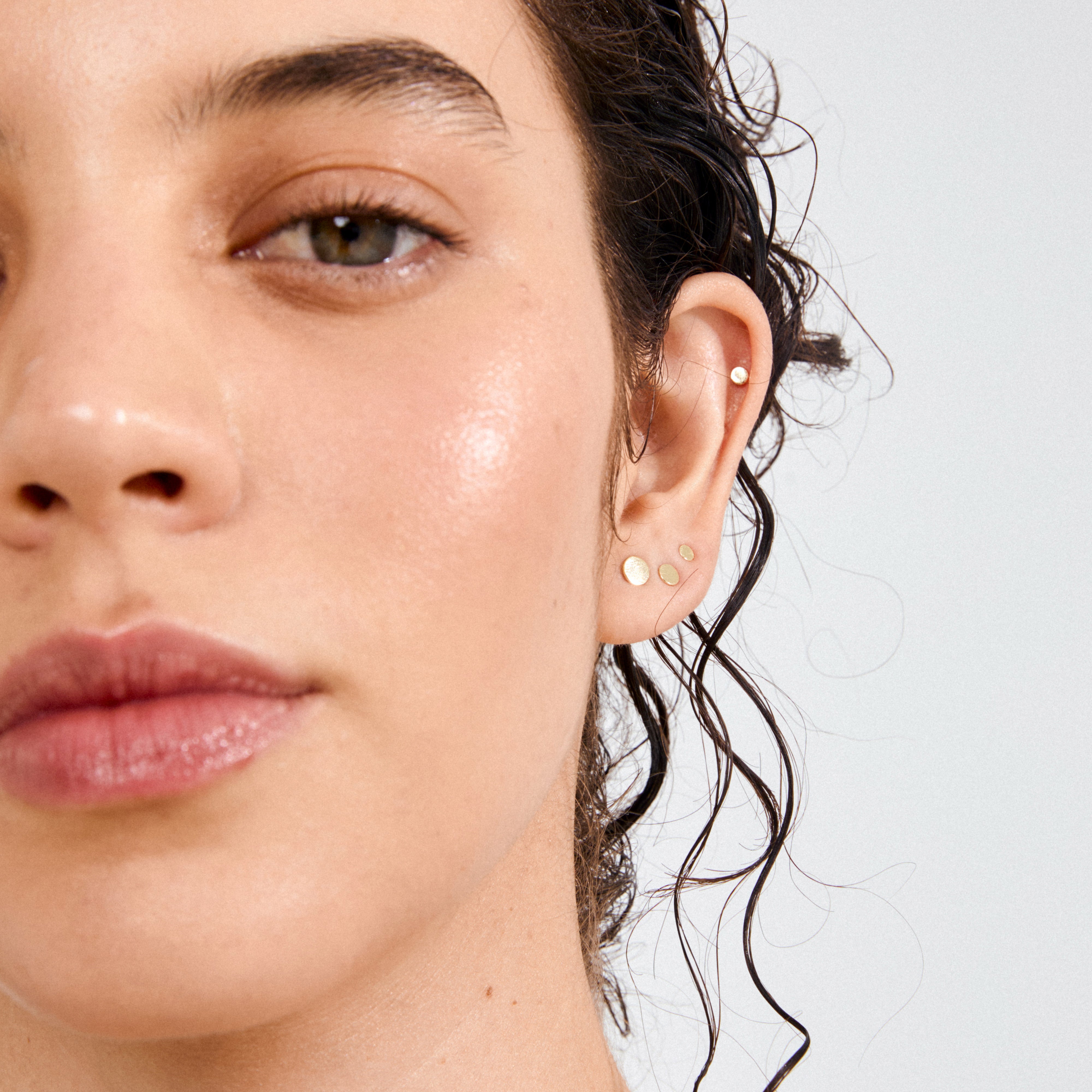 NORMA 3-in-1 set earrings gold-plated adorns ear, showcasing three descending stud sizes and a cartilage stud, perfect for versatile, stylish layering.