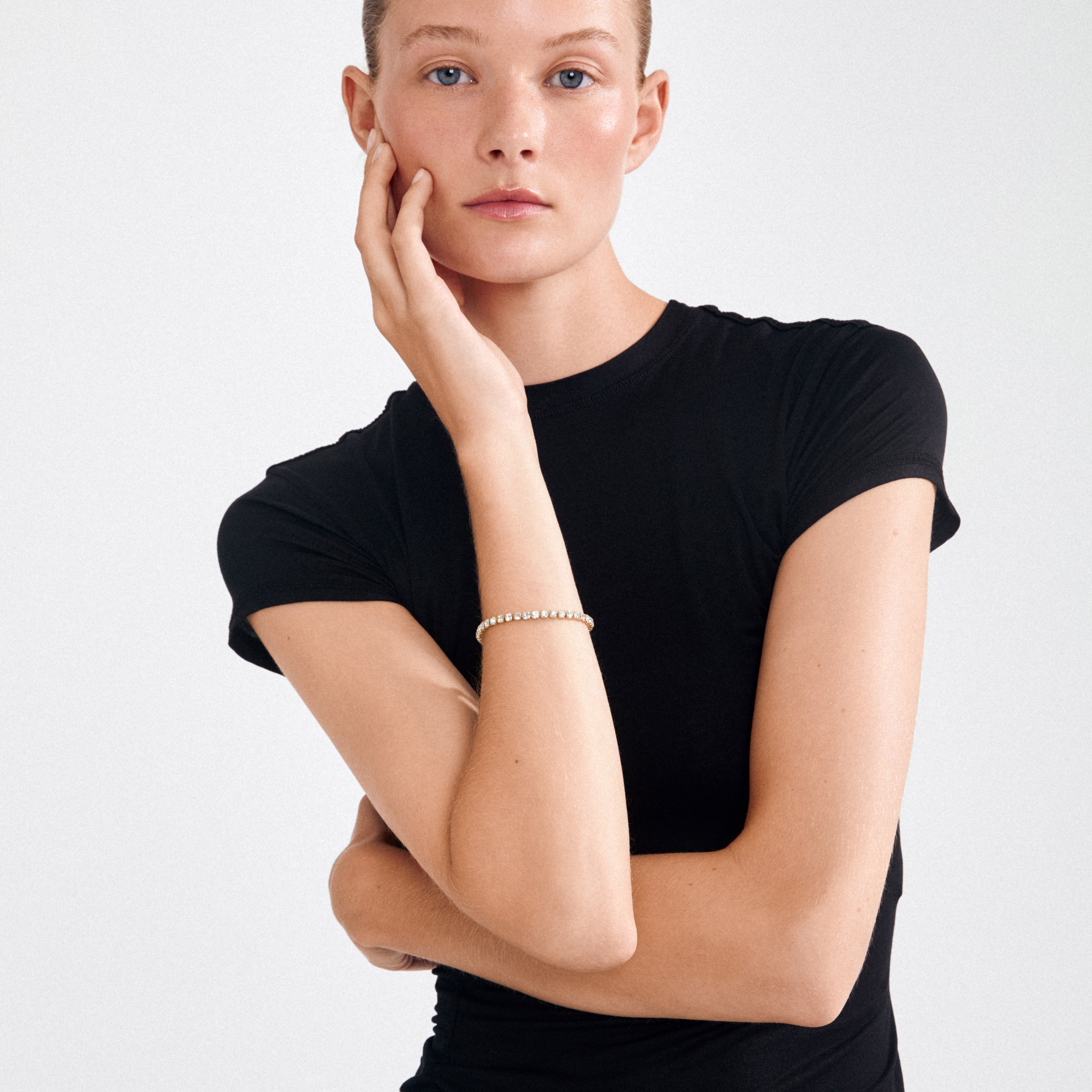 Young woman wearing LUCIA crystal bracelet, gold-plated with sparkling Preciosa crystals, showcasing minimalist elegance and Scandinavian quality in a timeless design.