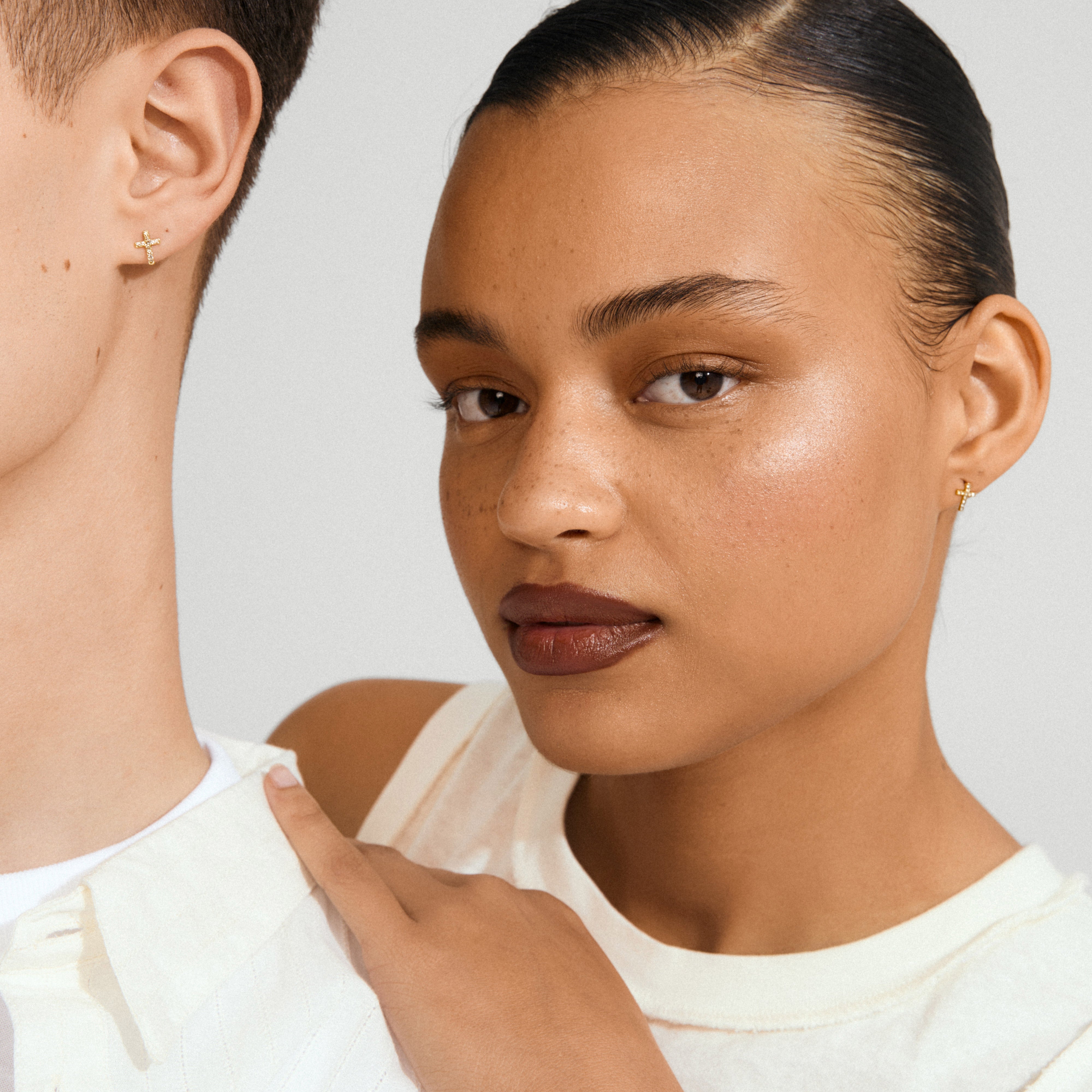 CLARA crystal cross earrings gold-plated adorn both individuals, catching light with their sparkling crystals, enhancing the chic, modern look of the wearer.