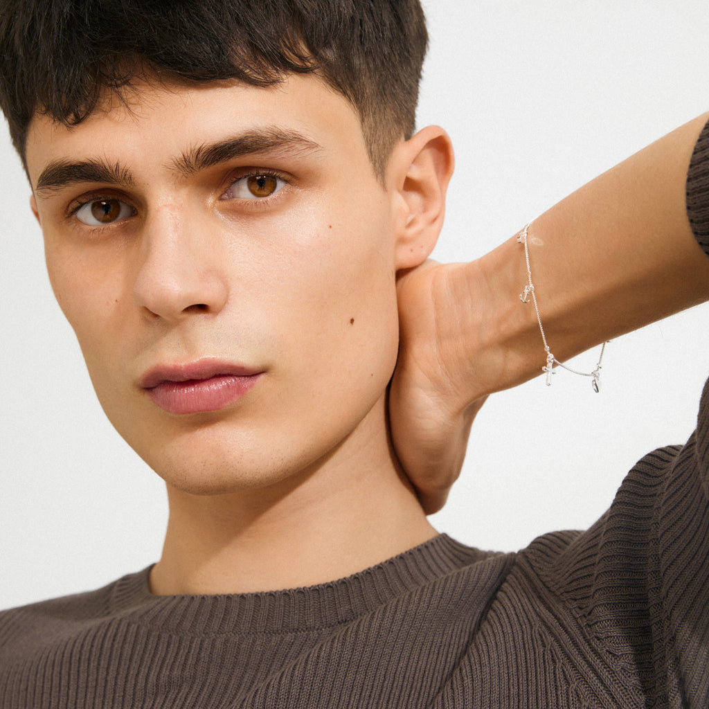 Young man wearing ANET crystal bracelet silver-plated, featuring faith, hope, and love pendants with Preciosa crystals, embodying Pilgrim's blend of timeless and trendy design.