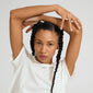 Young woman with braids wearing a PARISA flat link chain bracelet silver-plated, showcasing its delicate texture and reflective elegance against a plain white T-shirt.