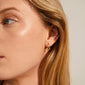 Close-up of a woman's ear adorned with ALBERTE organic shape gold-plated hoop earrings, showcasing their wavy, handcrafted design.