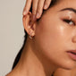 Close-up of a woman wearing Alberte organic shape hoop earrings, silver-plated, showcasing their wavy, nature-inspired design and shiny, handcrafted finish.