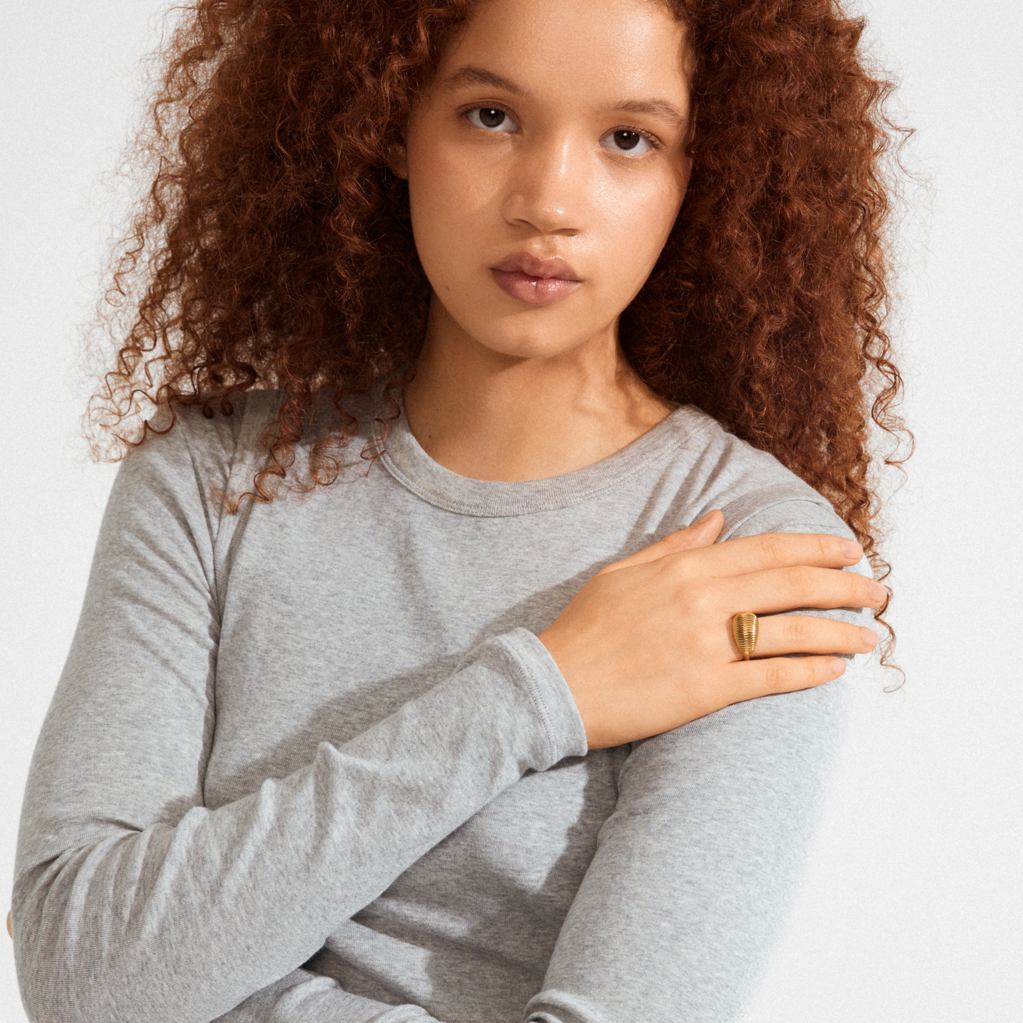 Young woman showcases the XENA ring gold-plated with groove textures on her middle finger, emphasizing its unique and classic design.