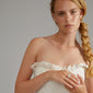 Woman wearing a white dress showcases the silver-plated XENA ring with a chunky, fluted design.