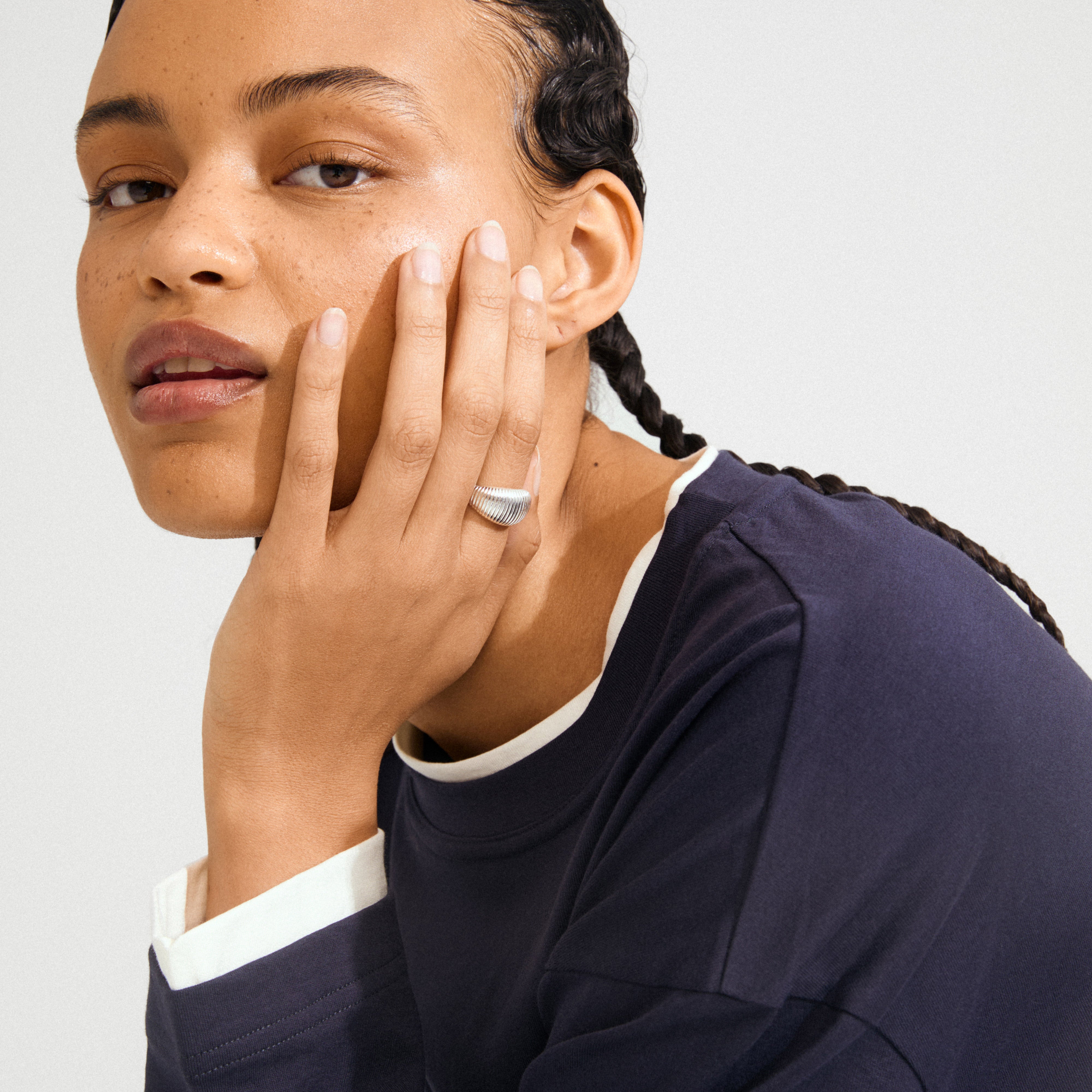 Close-up of a young woman showcasing the XENA ring, a silver-plated, ribbed statement piece on her hand, embodying Pilgrim's blend of timeless and trendy design.