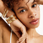 SOPHIA bangle bracelet gold-plated on woman's wrist, showcasing its shiny, classic design and click lock, paired with gold jewelry, highlighting Pilgrim's elegant style.