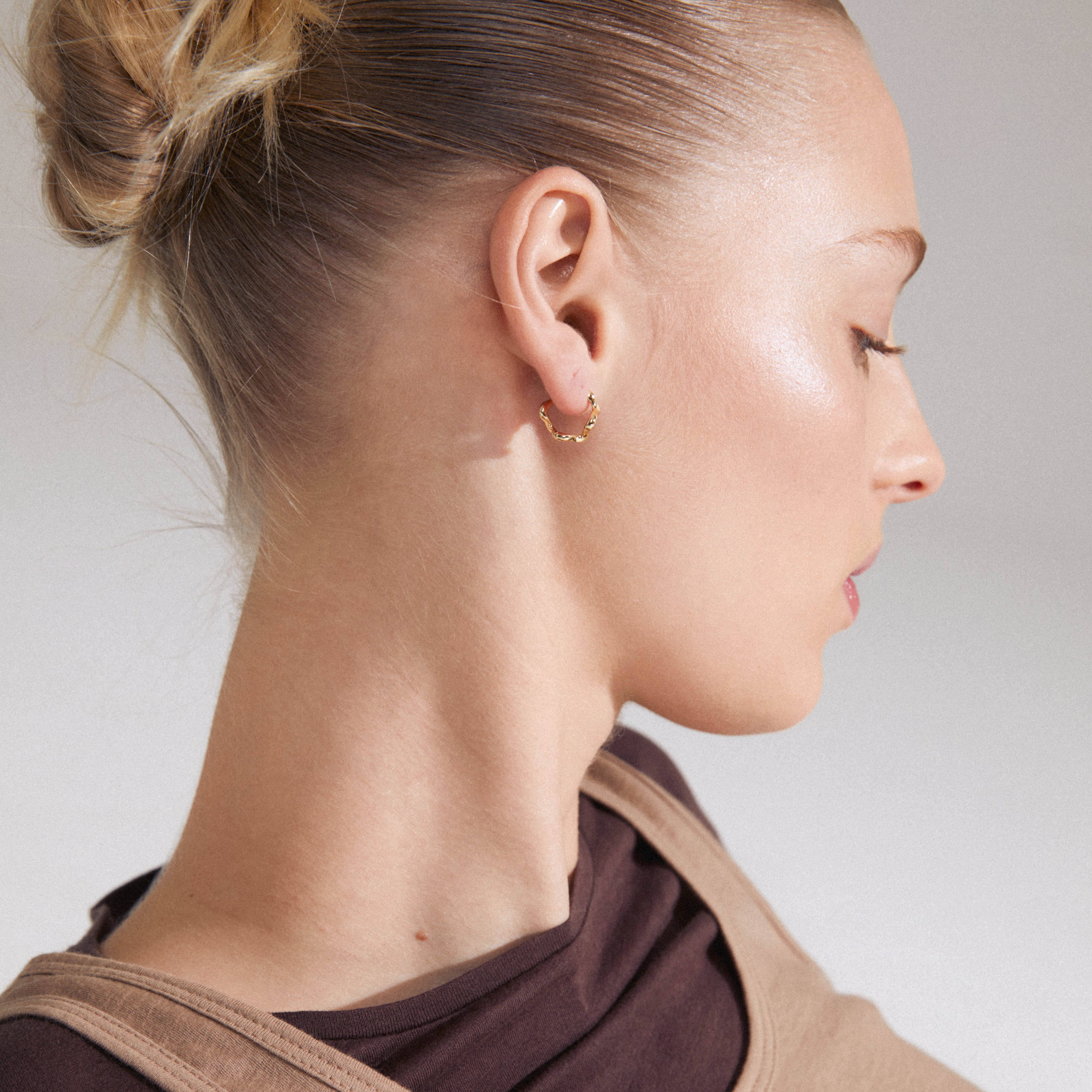 Gold-plated PENELOPE earrings showcased on a woman's profile, highlighting their elegant, curvy design and easy-to-use click clasp for chic styling.