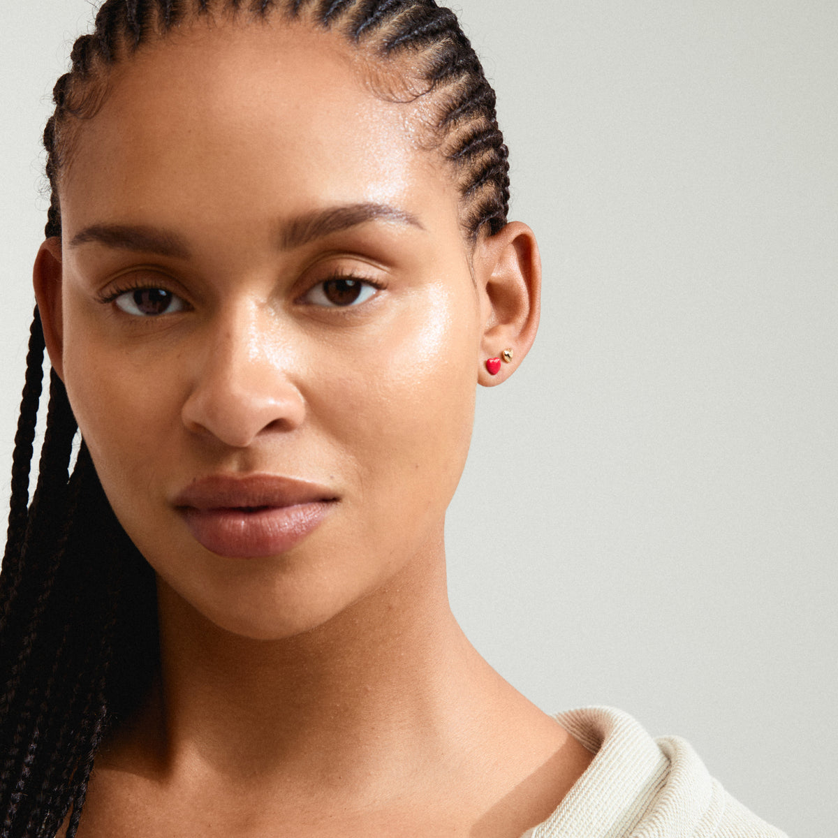 MAEVE earrings 2-in-1 set: woman with braided hair wearing gold-plated heart stud earrings from Pilgrim, showcasing elegant style and craftsmanship.