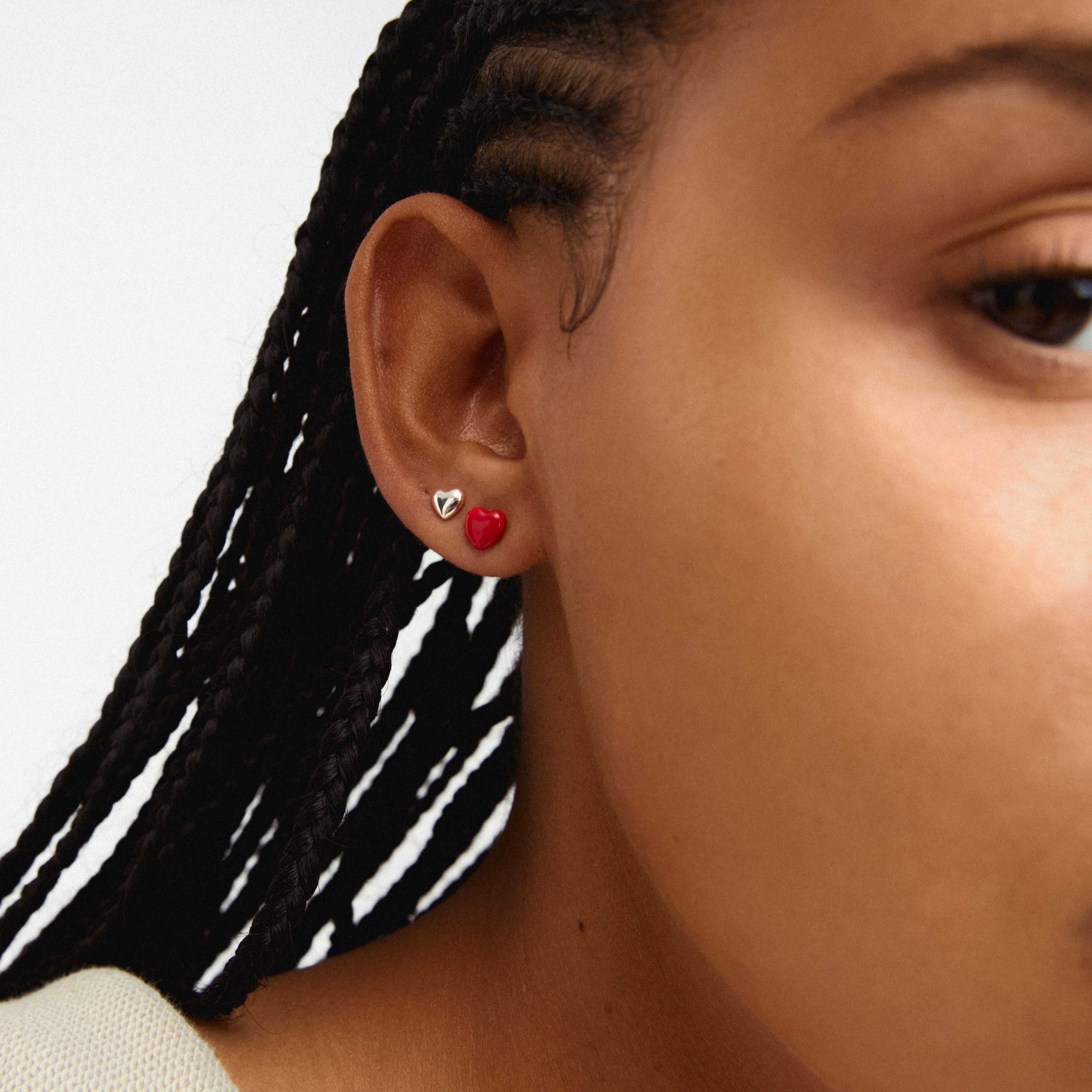 MAEVE earrings 2-in-1 set silver-plated: Close-up of a woman's ear adorned with sleek silver heart studs from Pilgrim's stylish and sustainable collection.
