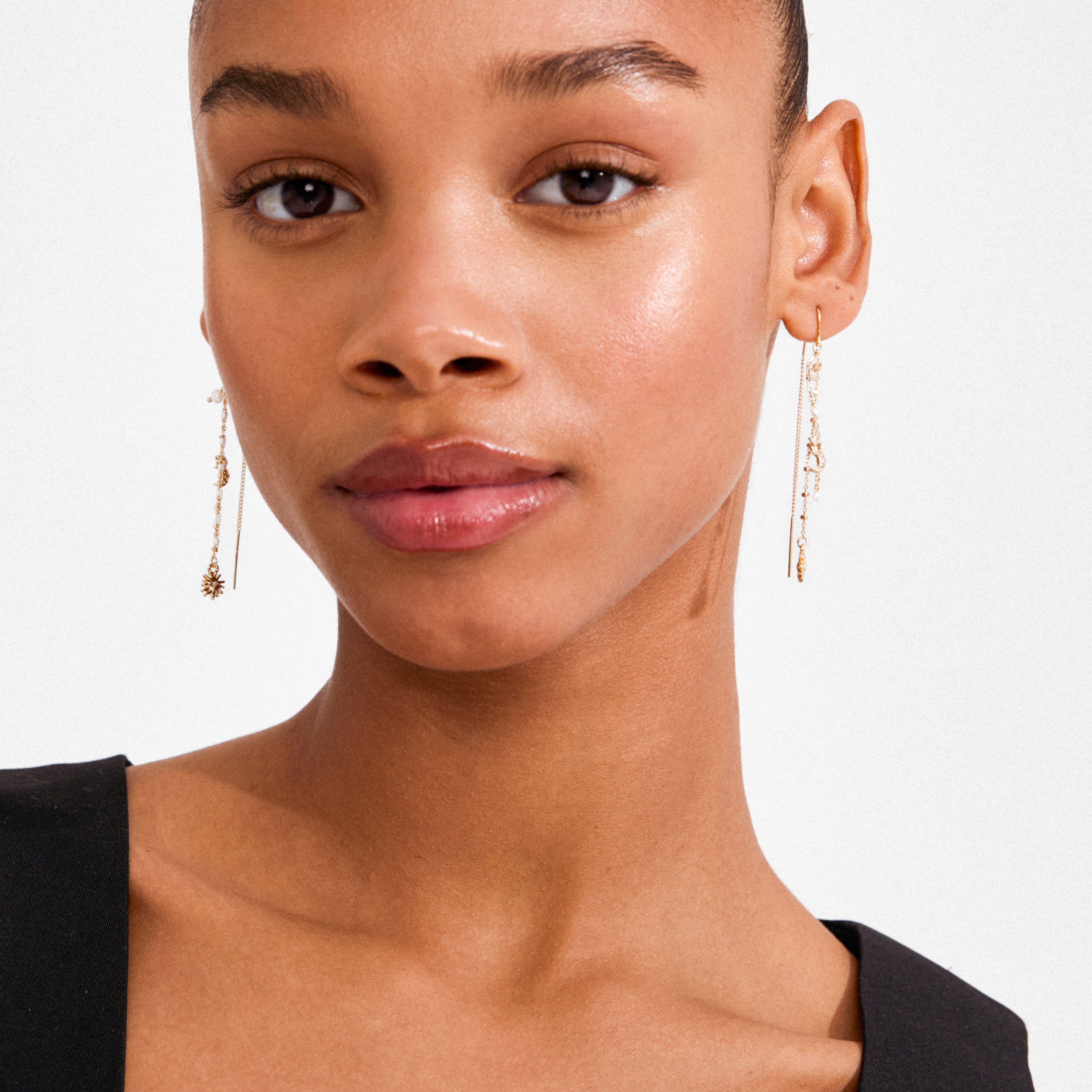 Model wears MYLAN chain earrings, gold-plated with starburst and crescent charms, showcasing Pilgrim's blend of luxe boho style and Scandinavian craftsmanship.