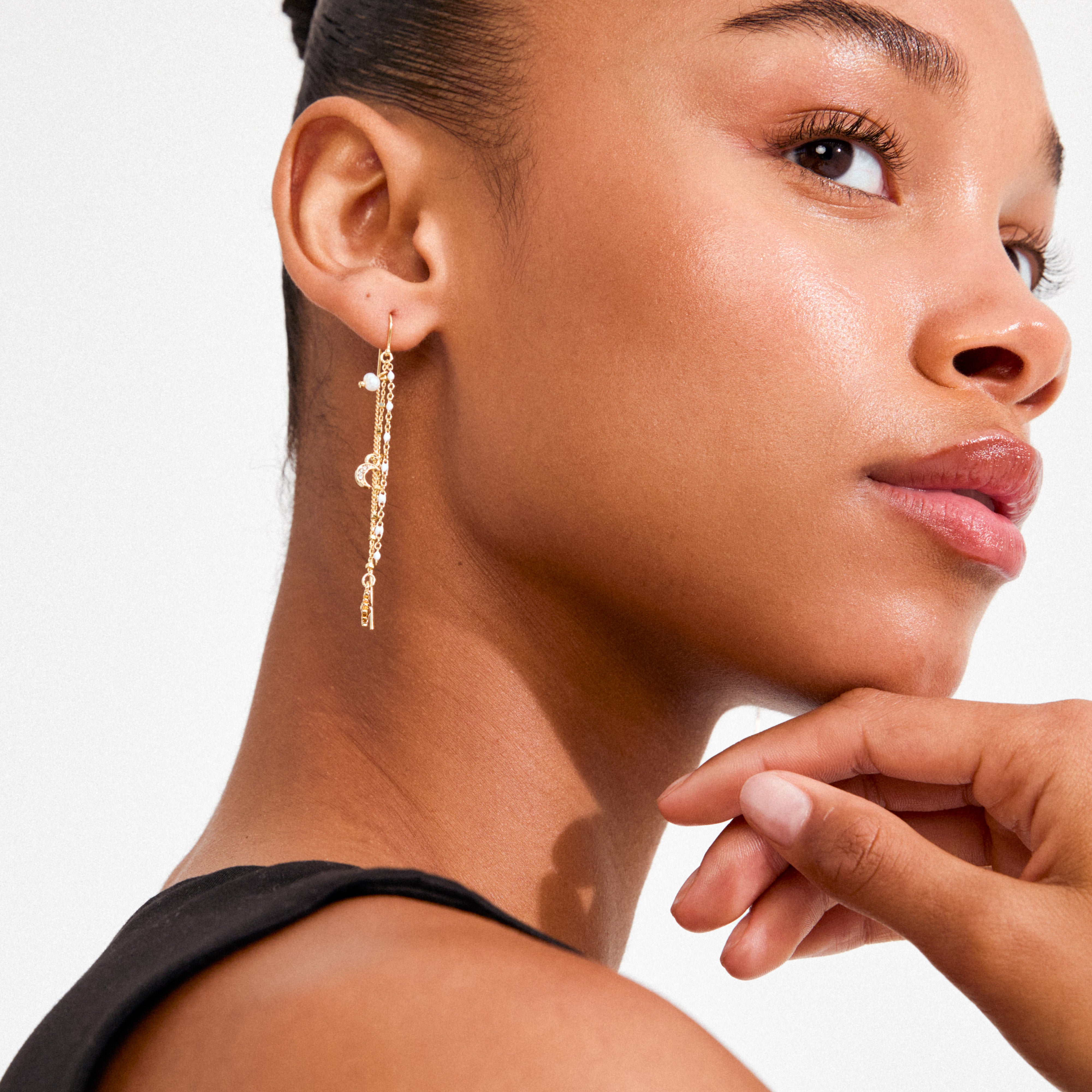 Young woman wearing gold-plated MYLAN chain earrings by Pilgrim, featuring delicate chains with pearl and crescent charms, embodying luxe boho vibes.