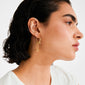 Close-up of MYLAN earrings gold-plated, featuring dangling chains and charms on a person's ear, showcasing Pilgrim's luxe boho style and soulful energy.