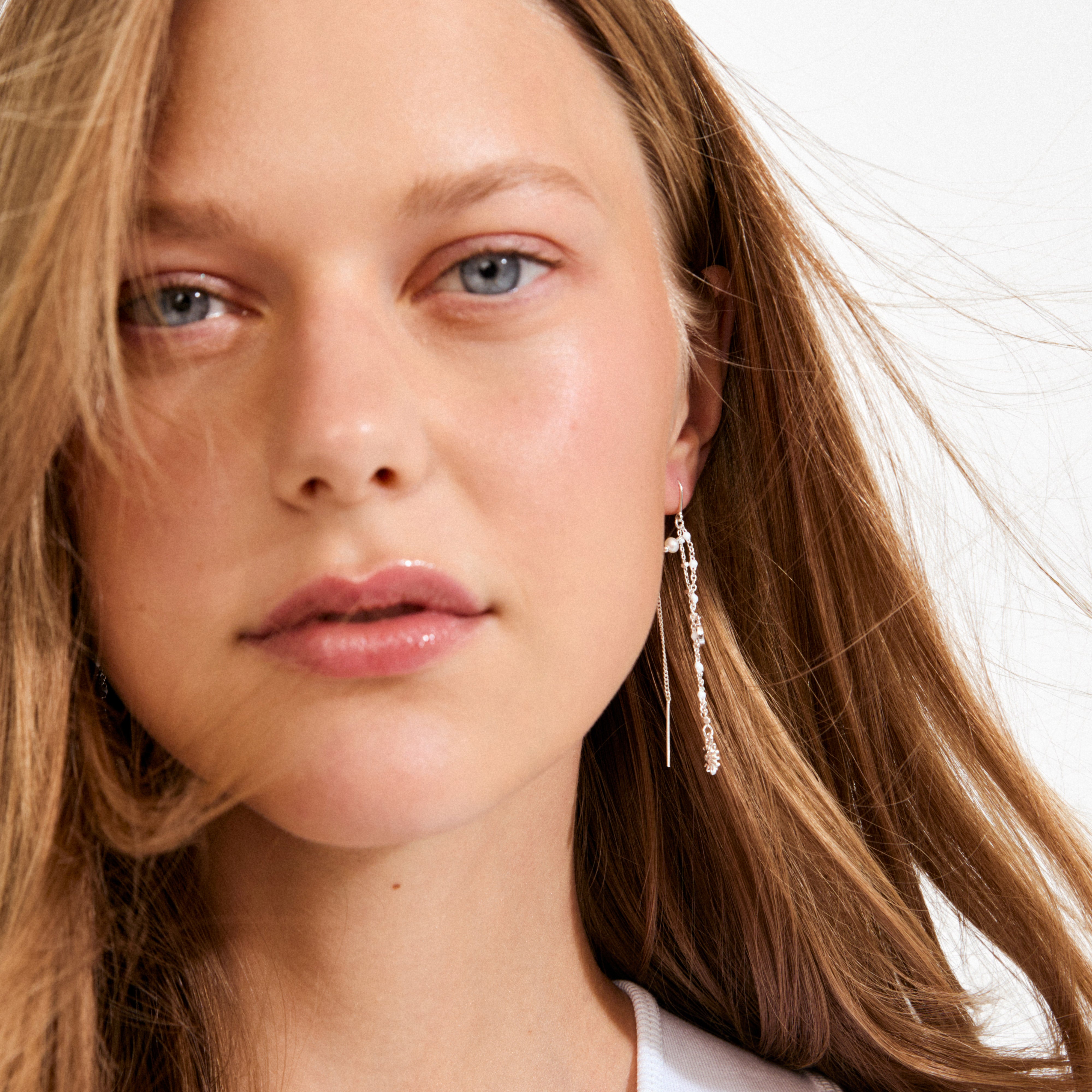 Young woman wearing Pilgrim’s MYLAN silver-plated chain earrings with delicate chains, small beads, and charms, embodying a luxe boho style and sustainable craftsmanship.