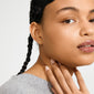 Close-up of a woman wearing AVA star earrings gold-plated with a satin-matt finish, highlighted by her slicked-back hair and soft gray sweater.