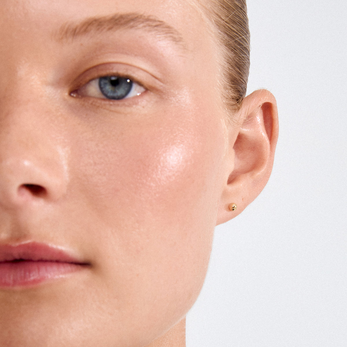 Close-up of a person wearing MOLLY earstuds gold-plated, featuring a tiny pearl, showcasing Pilgrim's Scandi minimalist design aesthetic.