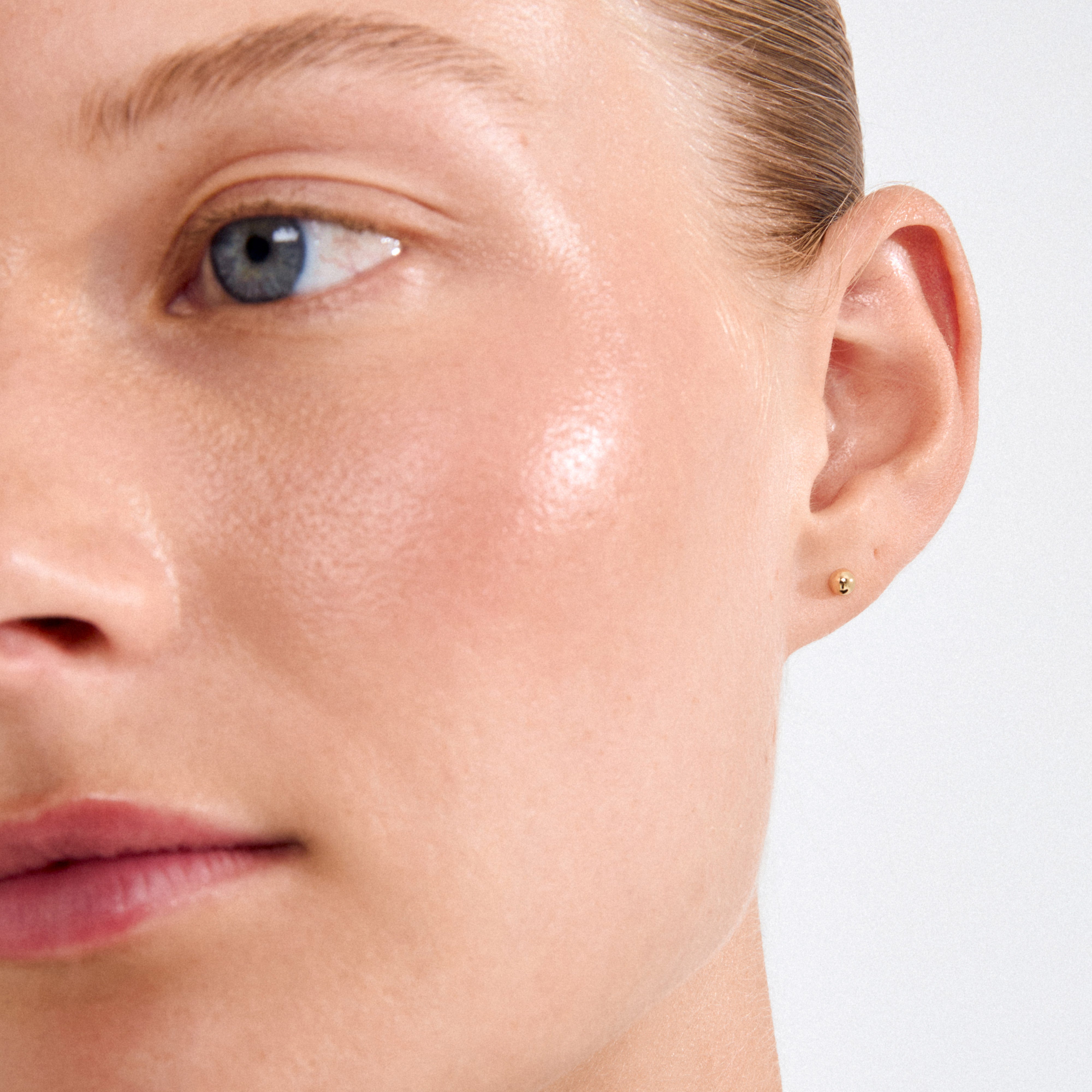 Close-up of a person wearing Pilgrim's MOLLY earstuds gold-plated, a tiny pearl earring, embodying Scandi minimalism and crafted from recycled materials for an effortless look.