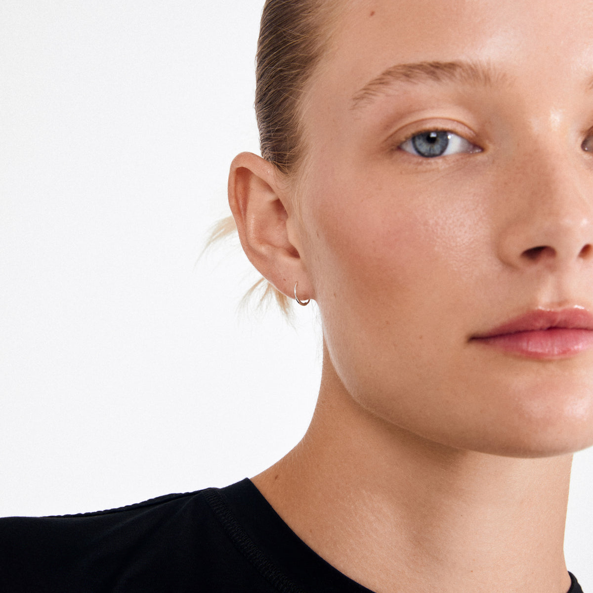 Close-up of RAQUEL mini hoop earrings, silver-plated, showcased on an ear. Crafted from 99% recycled materials, these elegant, timeless creoles complement any outfit.