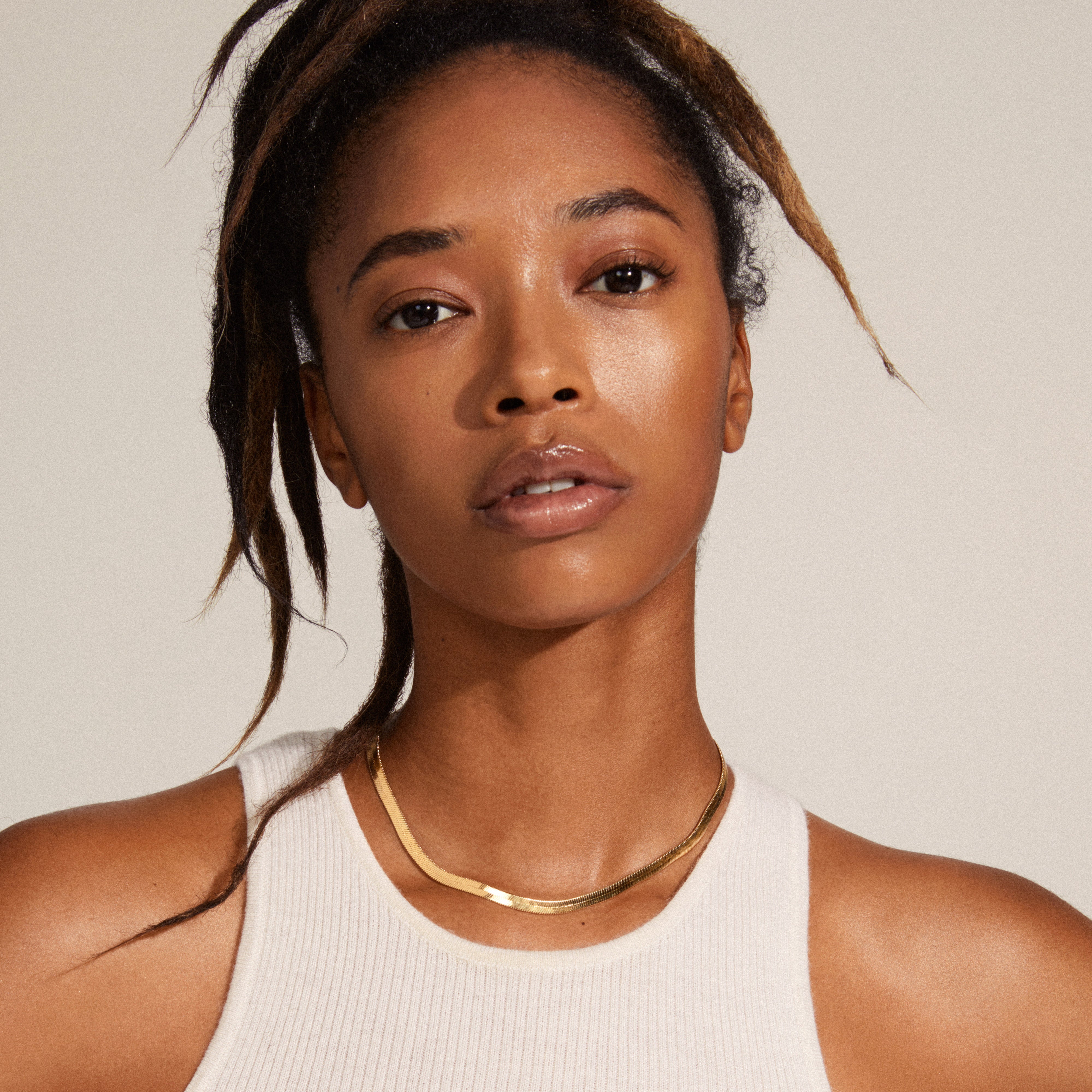 NOREEN flat snakechain necklace gold-plated elegantly wraps around a person's neck, showcasing its polished, textured links in a stylish, exotic pattern.
