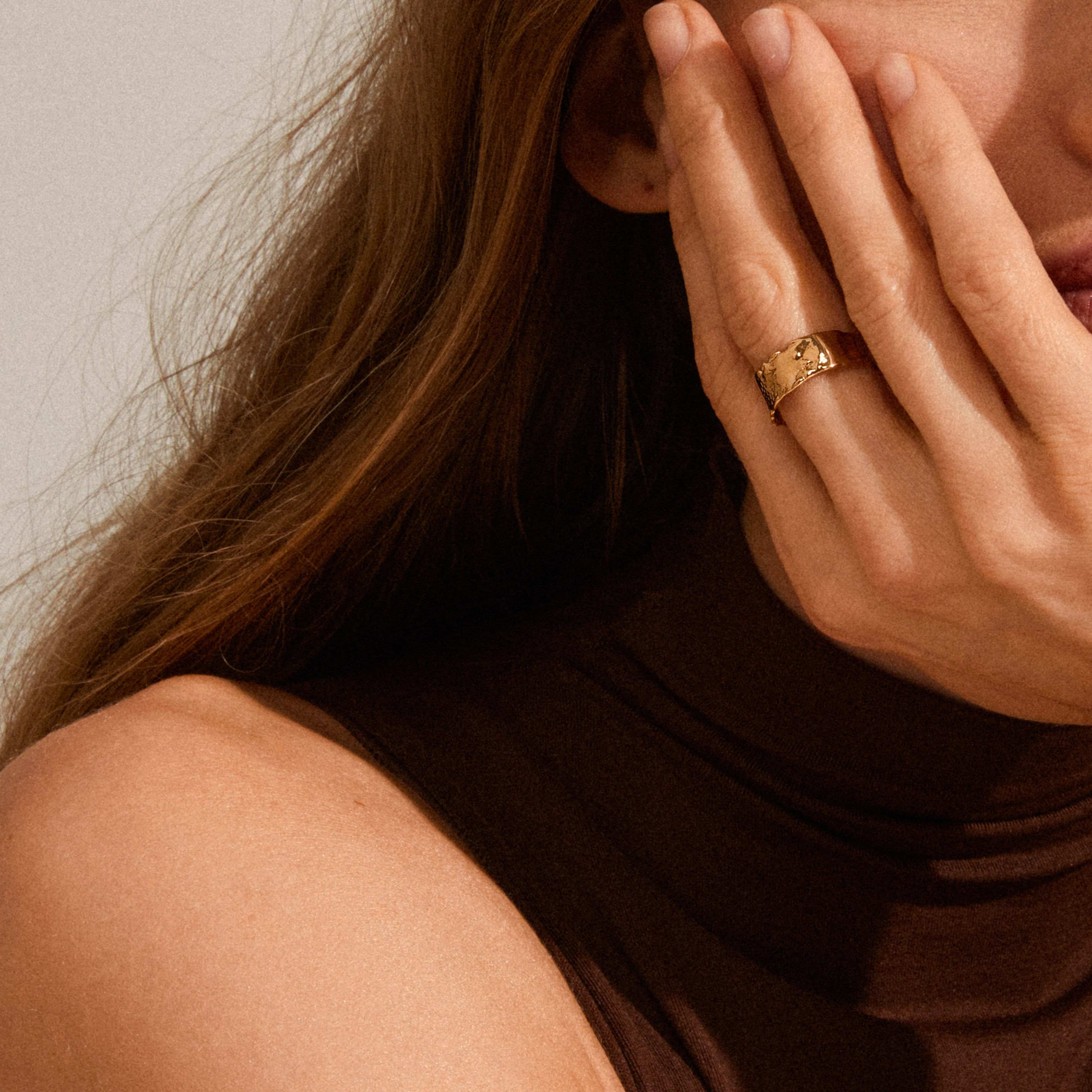 Close-up of a woman's hand showcasing the BATHILDA rustic ring gold-plated, featuring a textured, hammered finish for a unique, stylish look.